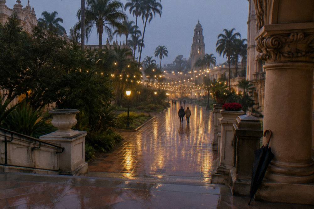 Festival lights strung above a park promenade at dusk