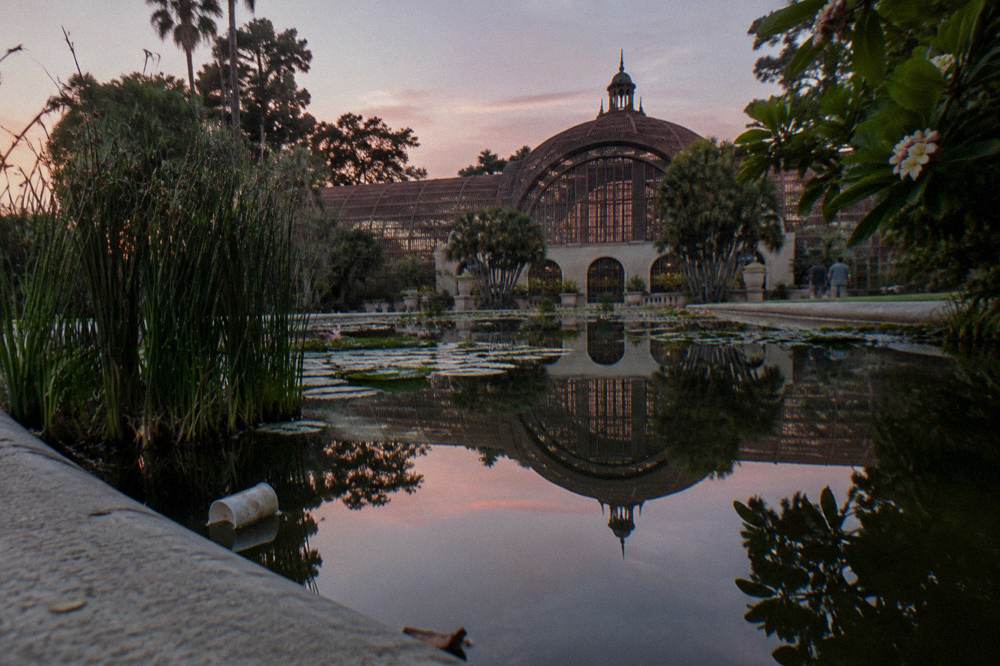 Botanical building with lattice arches reflected in a still lily pond