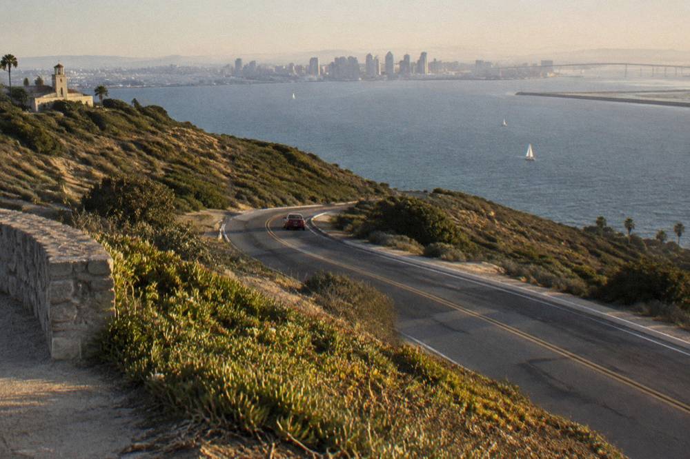 A coastal road curving along the Point Loma peninsula toward the bay