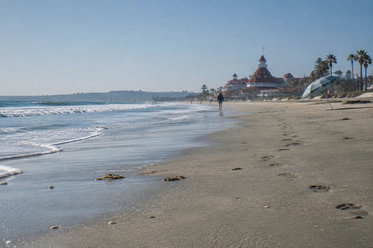 Wide sandy beach with gentle waves rolling in under a clear sky
