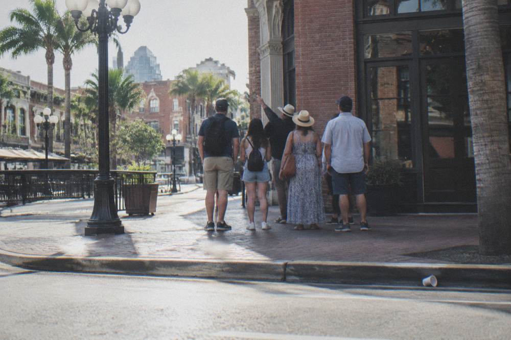 A guide speaking with a small group of visitors gathered on a downtown sidewalk