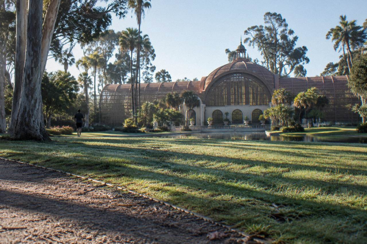 Lath building facade and garden paths across an open lawn in Balboa Park