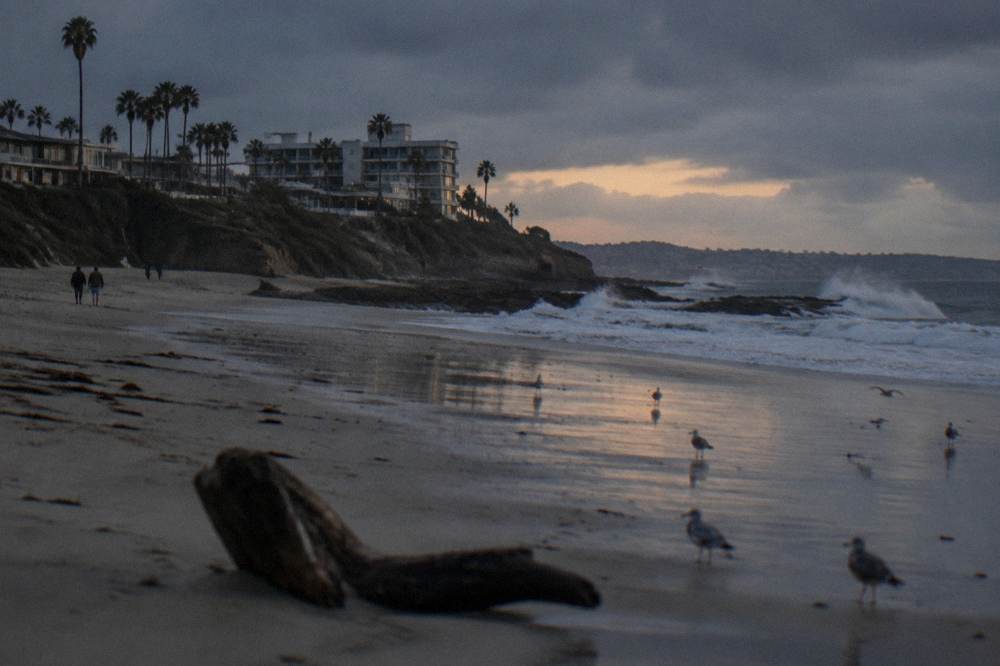 Waves breaking on dark rocks along the La Jolla coastline at golden hour