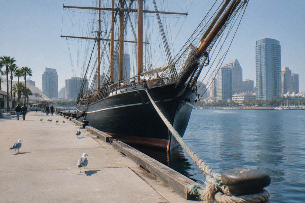 Historic ships moored along the downtown San Diego waterfront with city buildings behind