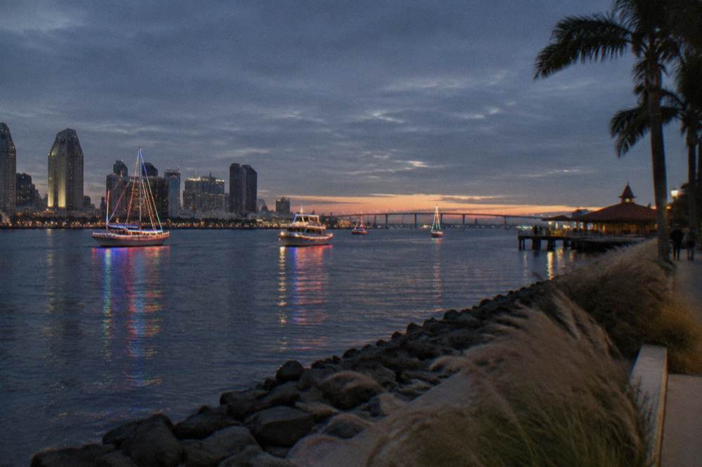 Decorated boats with bright lights passing along the bay at dusk