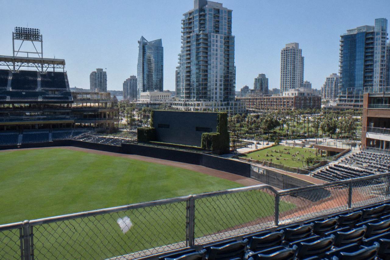Grass lawn rising above a ballpark outfield with downtown buildings behind it