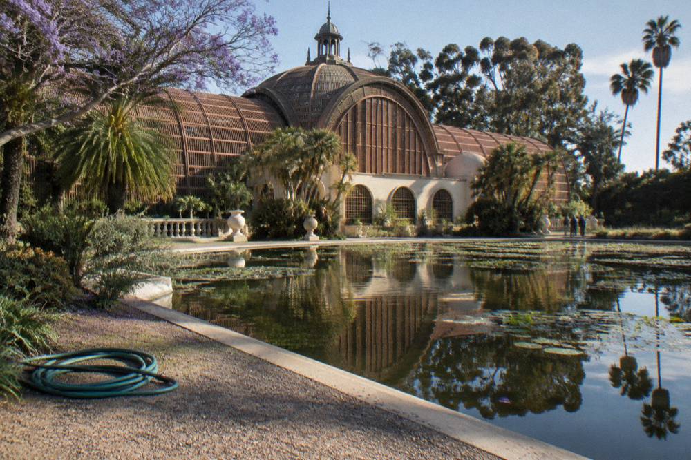 Gardens and a curved colonnade building in Balboa Park on a clear day