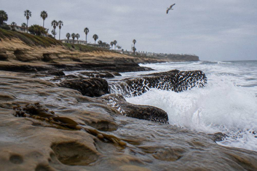 Waves breaking over rocks at the base of the cliffs with open ocean beyond