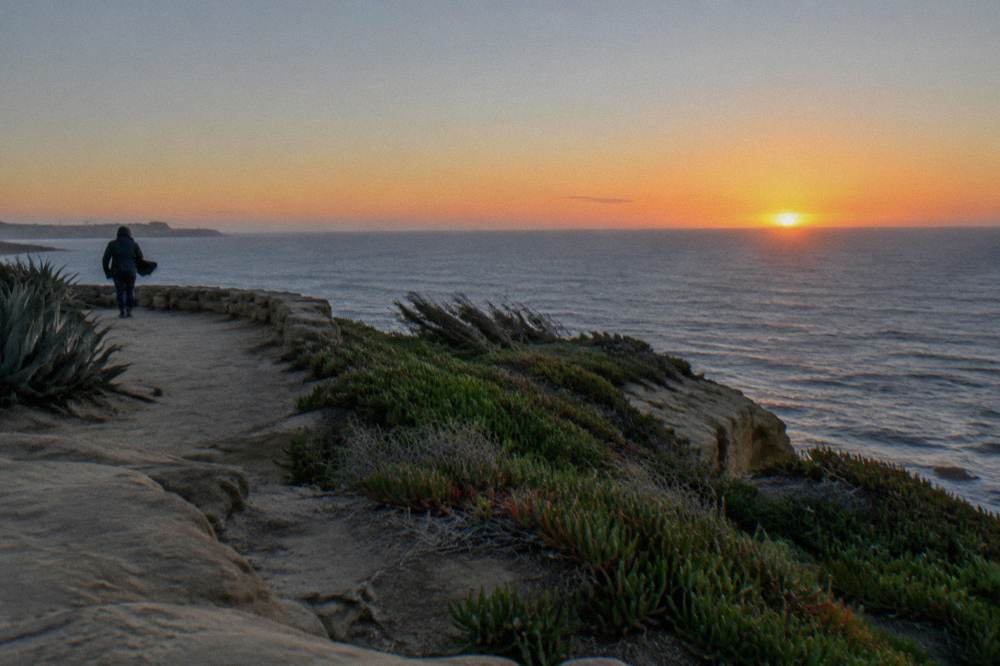 Open ocean horizon glowing at dusk seen from a clifftop overlook