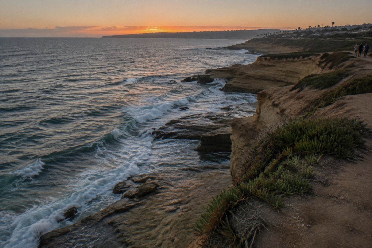 Ocean waves breaking below sandstone cliffs along the Sunset Cliffs shoreline at dusk