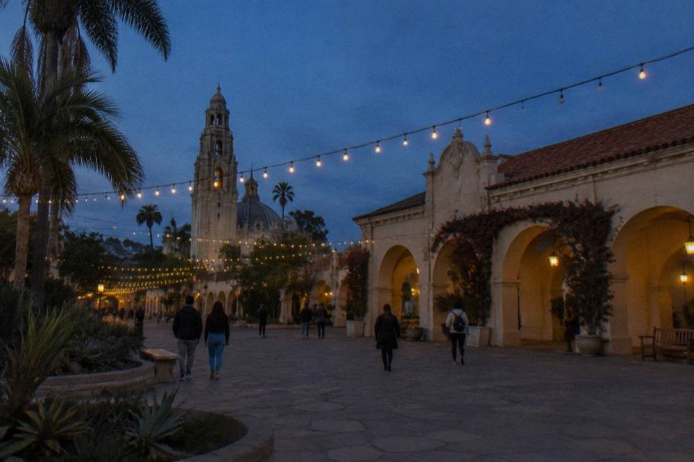 Strings of festival lights above a Balboa Park plaza at dusk