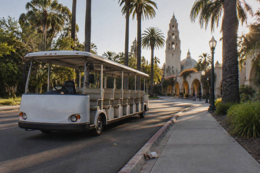 Shuttle tram waiting at a stop along a Balboa Park walkway