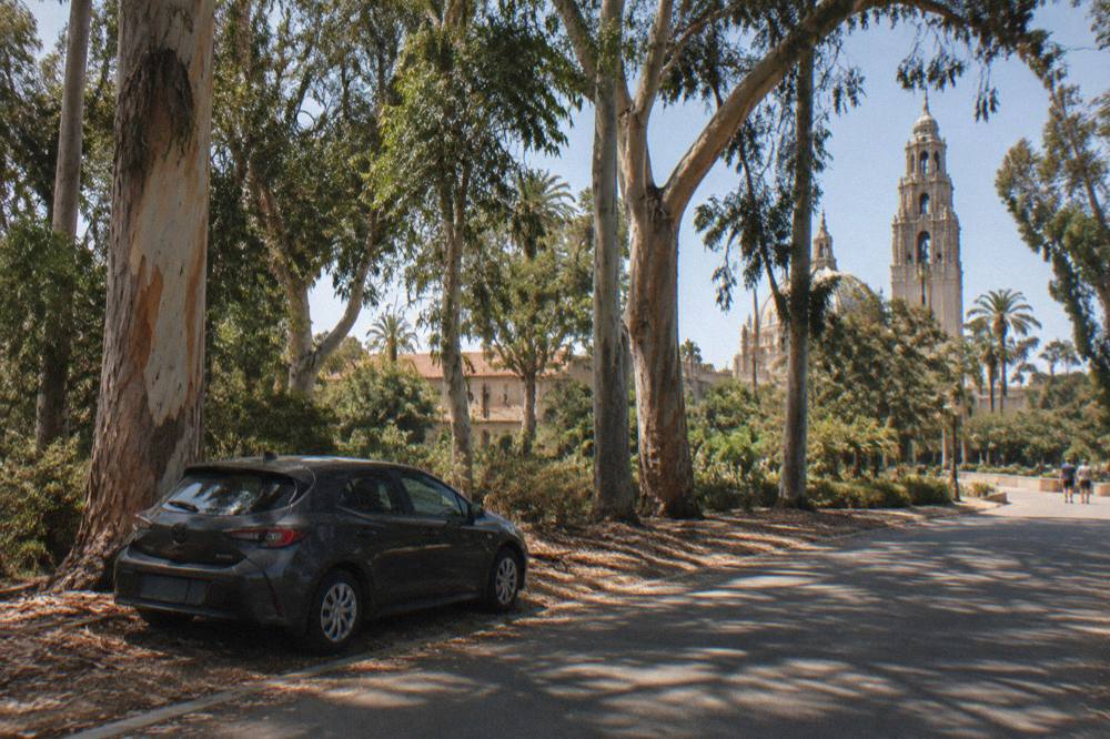 Car parked under trees near a Balboa Park entrance road