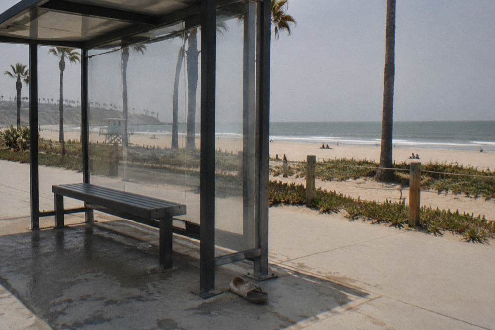 Bus shelter on a coastal street with sand and water beyond