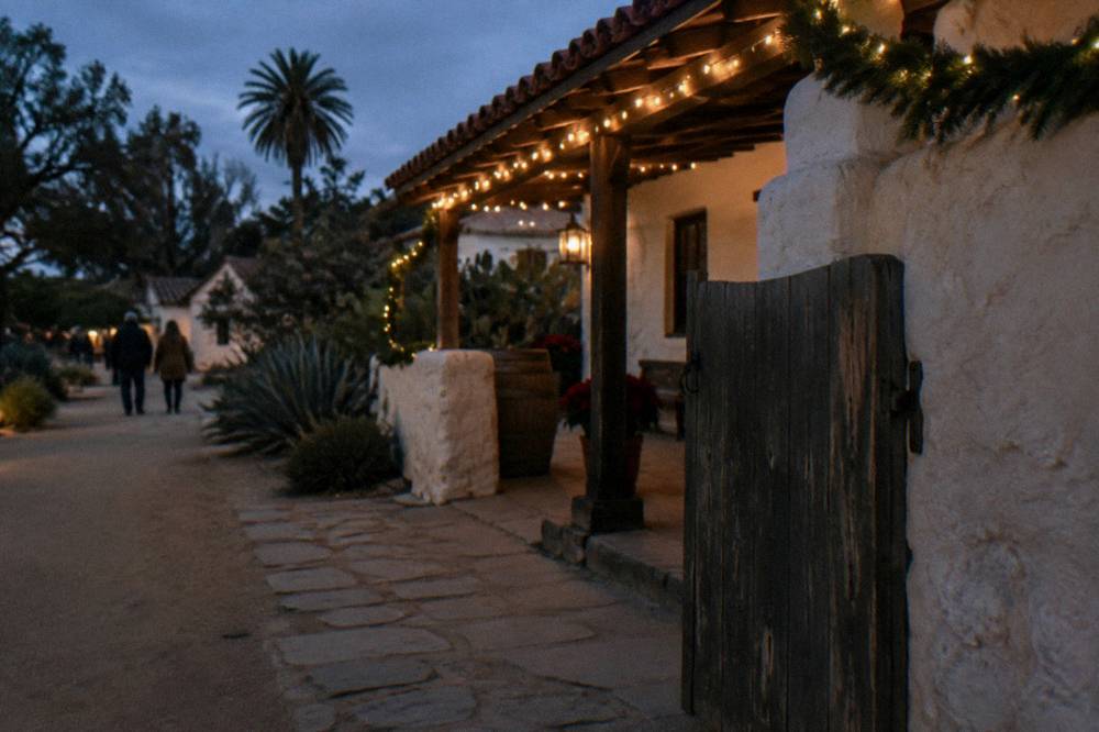 A historic building facade decorated with festive lights and greenery at night