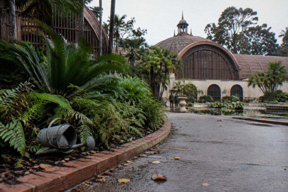 A lath botanical building with lush planting beds along a garden path in a public park