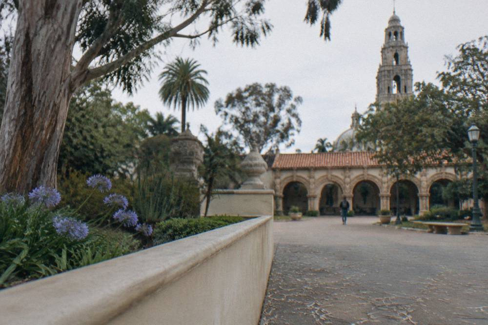 Balboa Park plaza with gardens and a historic building facade in the background