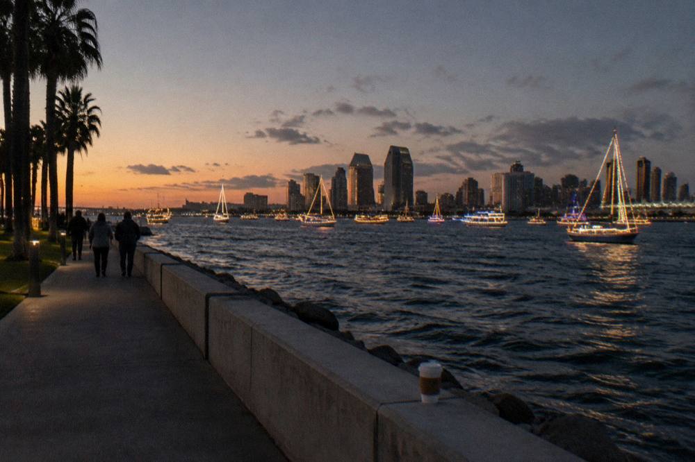 Decorated boats with strings of lights gathered on dark bay water at dusk