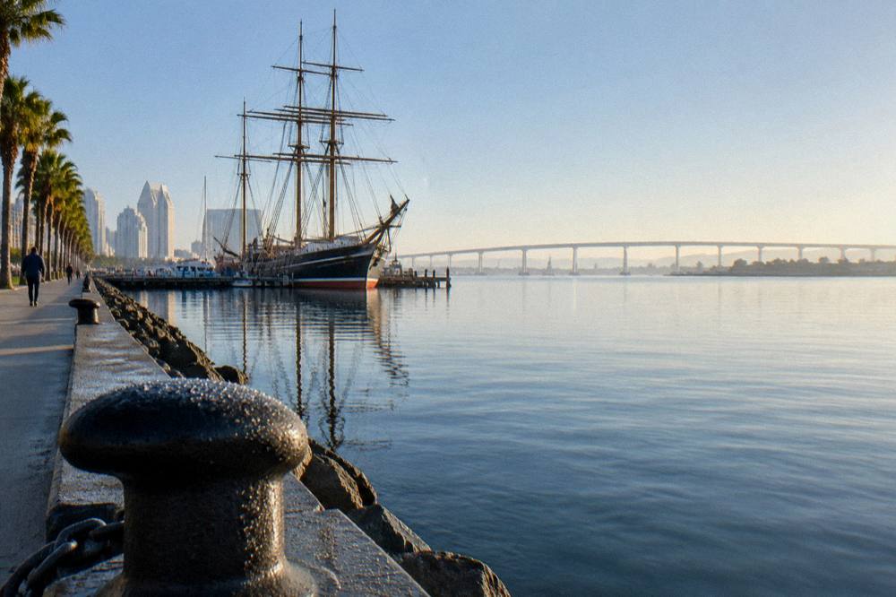 Waterfront promenade with a historic ship and bay views