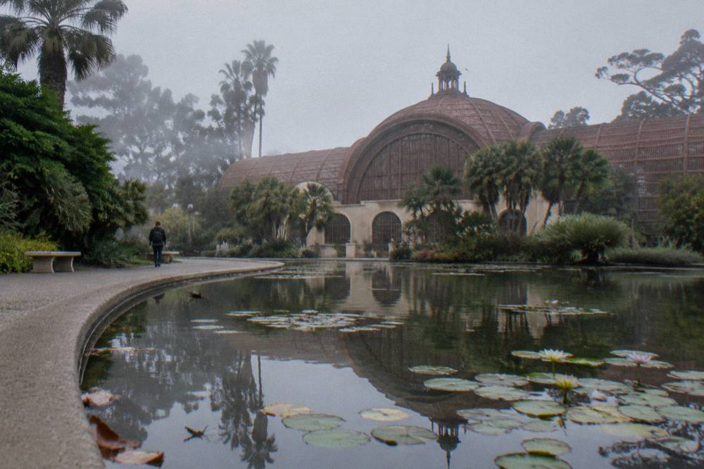 The lath walls of the Botanical Building beside a still reflecting pool