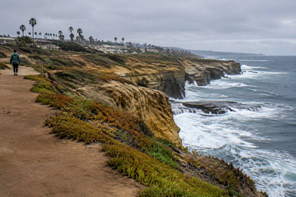 Waves breaking below sandstone cliffs along a coastal path